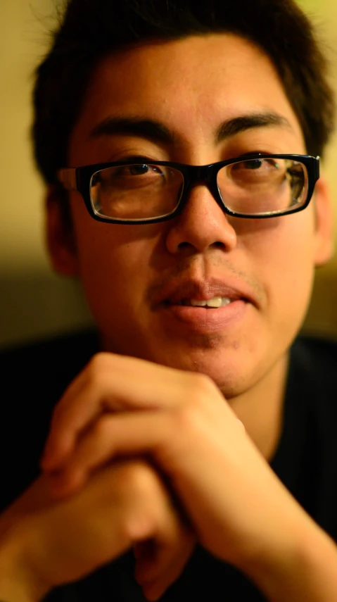 a man wearing glasses with his chin resting on his arm