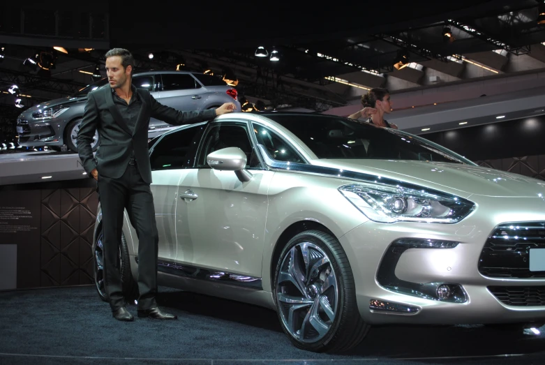 a man leaning on the wheel of a silver car