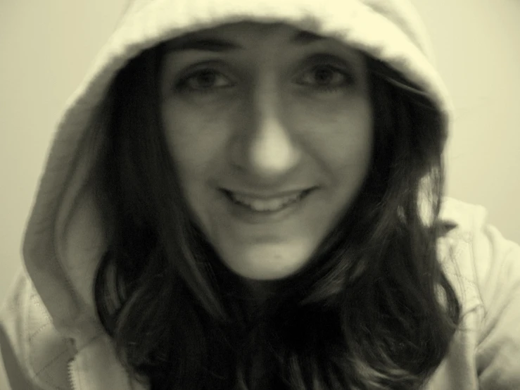 a woman wearing a hoodie smiles at the camera