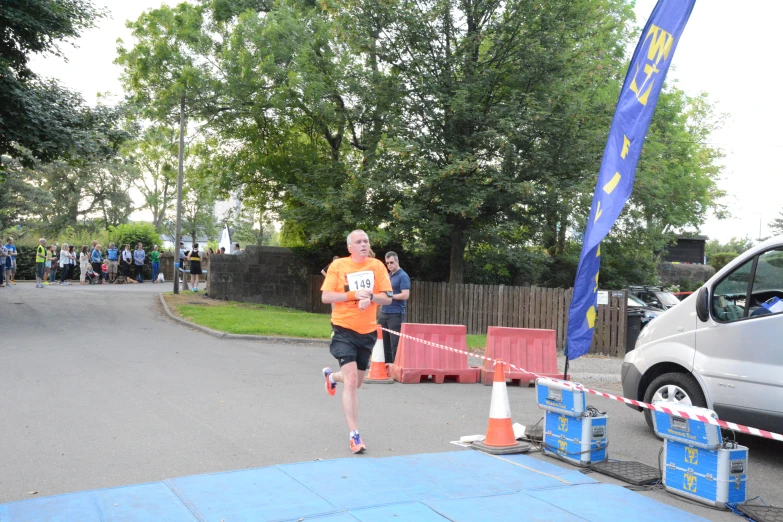 man running on sidewalk with orange vest and blue cones