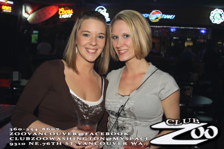 two women pose for the camera with drinks