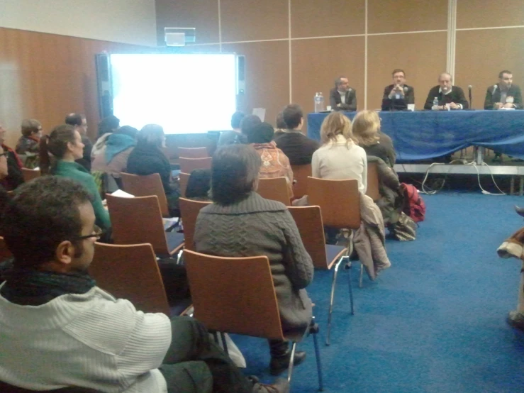 several people seated in chairs in front of a speaker