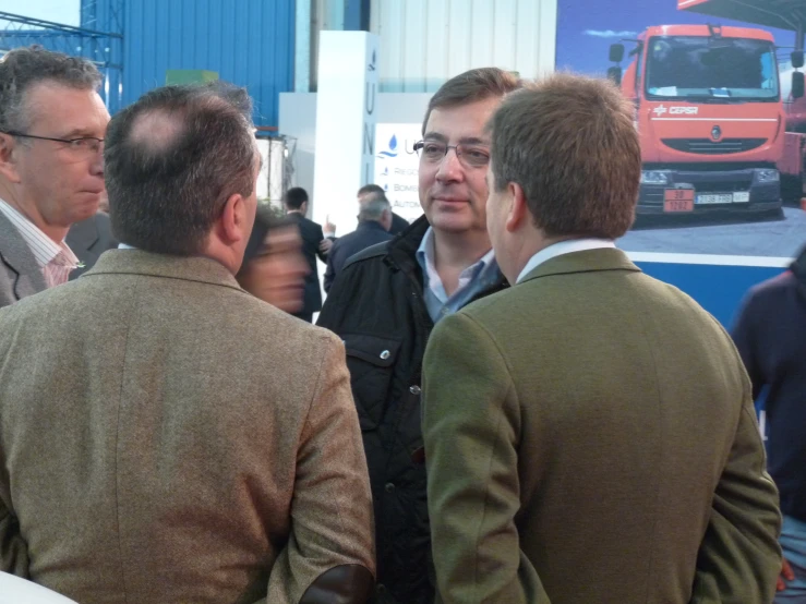 people talking at an event while looking at a truck on display