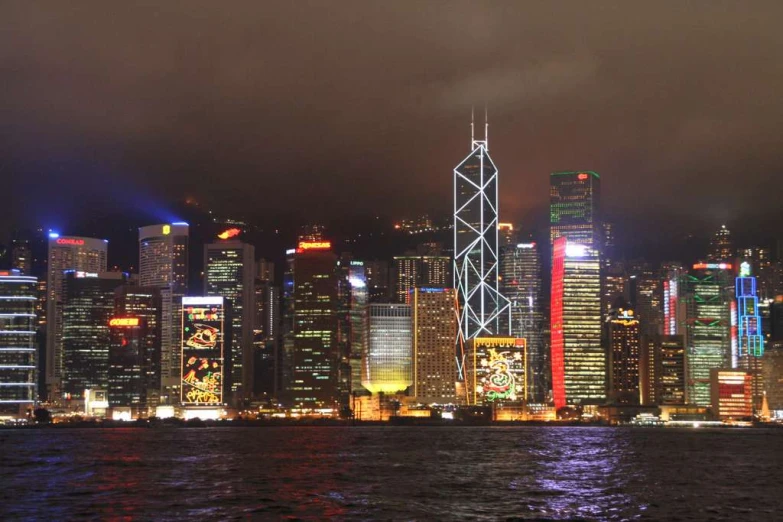 the city skyline at night with the lights of many different buildings