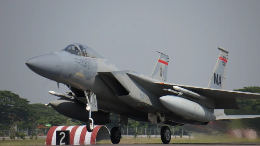 a fighter jet with two people on the bottom landing strip