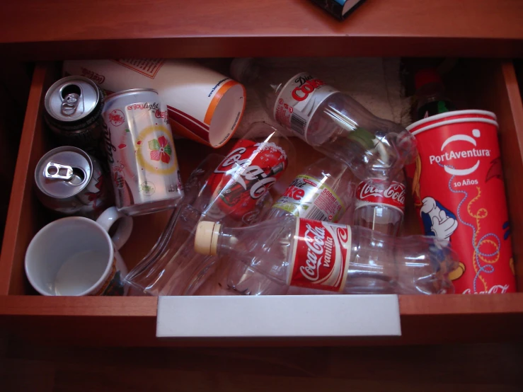 the inside of an open drawer filled with bottles and cups