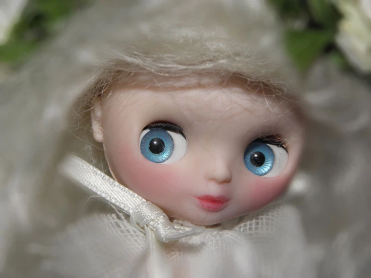 doll with blue eyes and dress sitting in fluffy white material