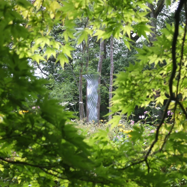 the trees and bushes surrounding a sculpture stand out in the green