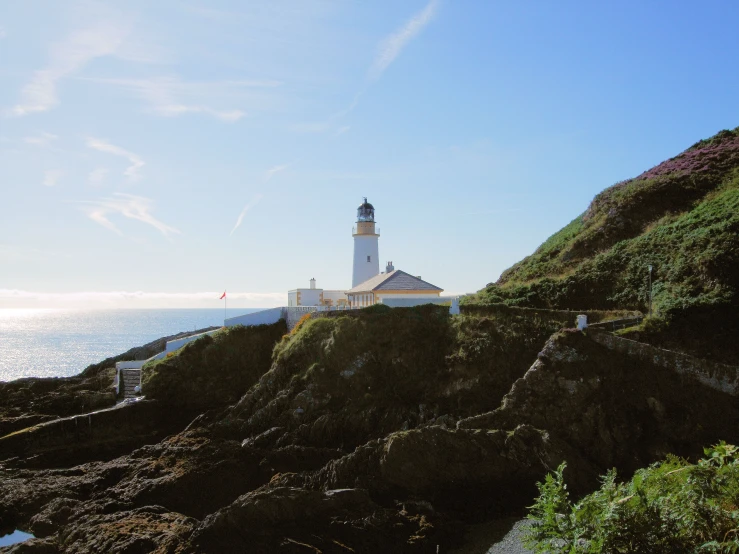 a white light house sitting on top of a cliff