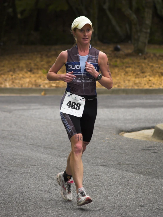 a woman running across a road wearing a bib and hat