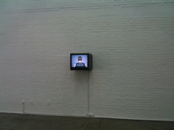 tv on the wall with a white bricked background