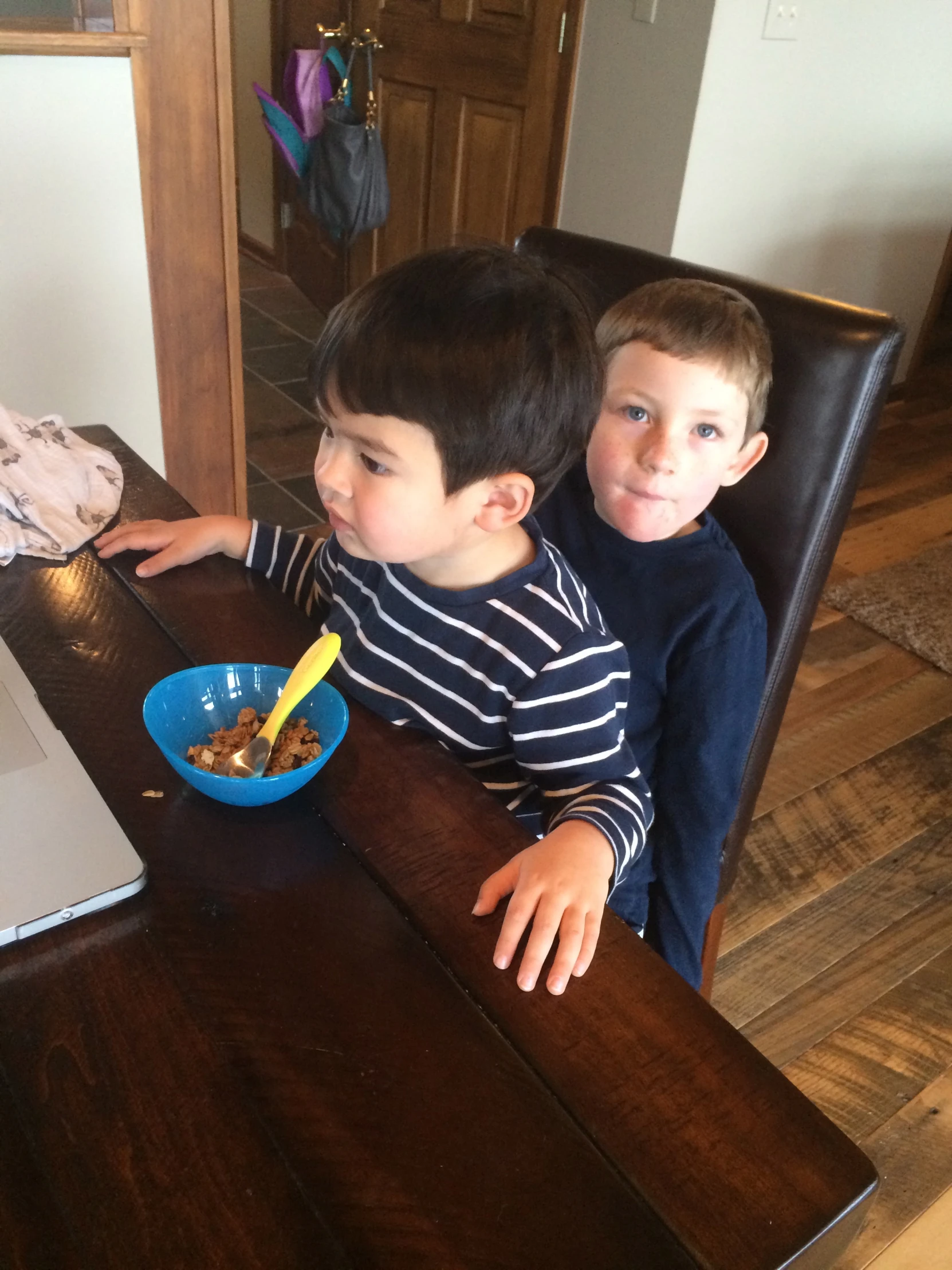 two boys sitting at a table eating food