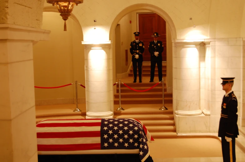 two soldiers in formal clothing stand next to an american flag