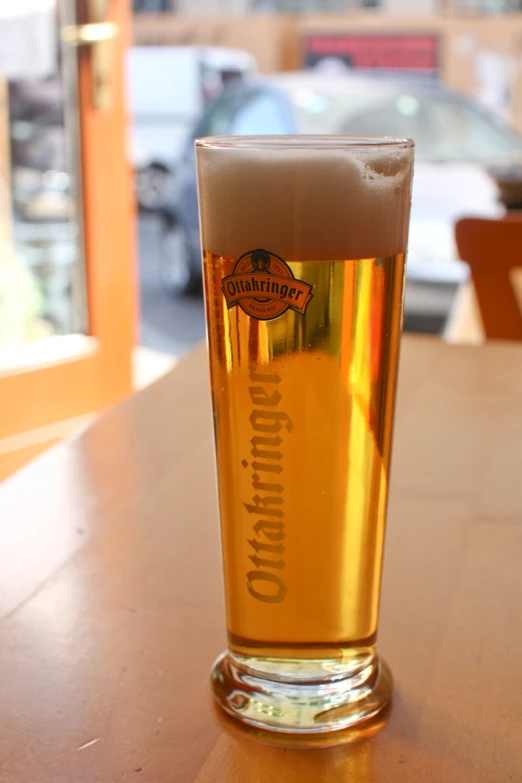 a tall glass full of beer sits on the bar