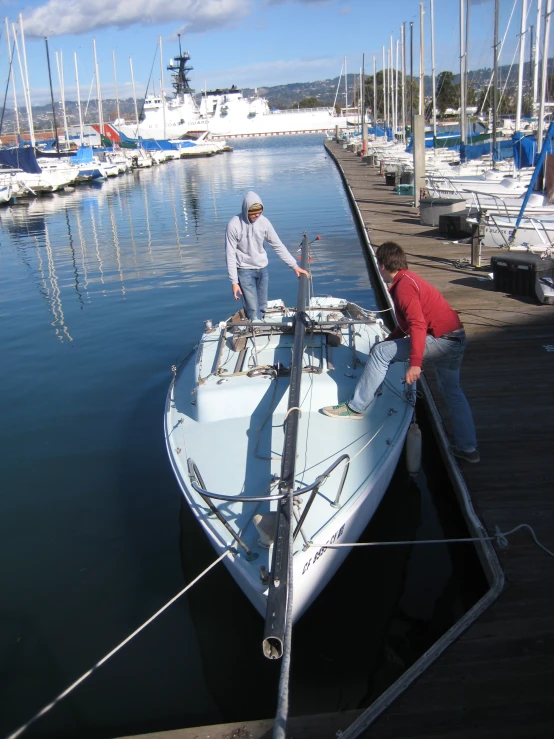 two men working on a sail boat docked in the water