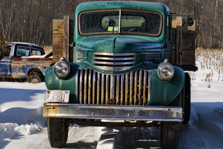 an old truck parked on a snowy path next to another car