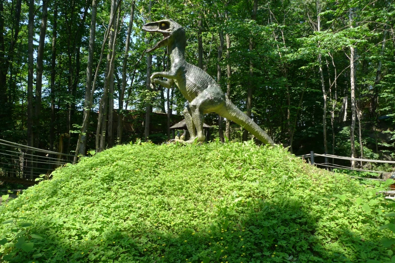 a dinosaur statue that is sitting on a pile of grass