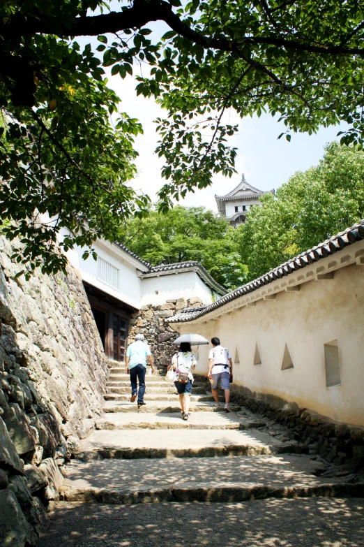 three people walking up stairs in an alley between some buildings