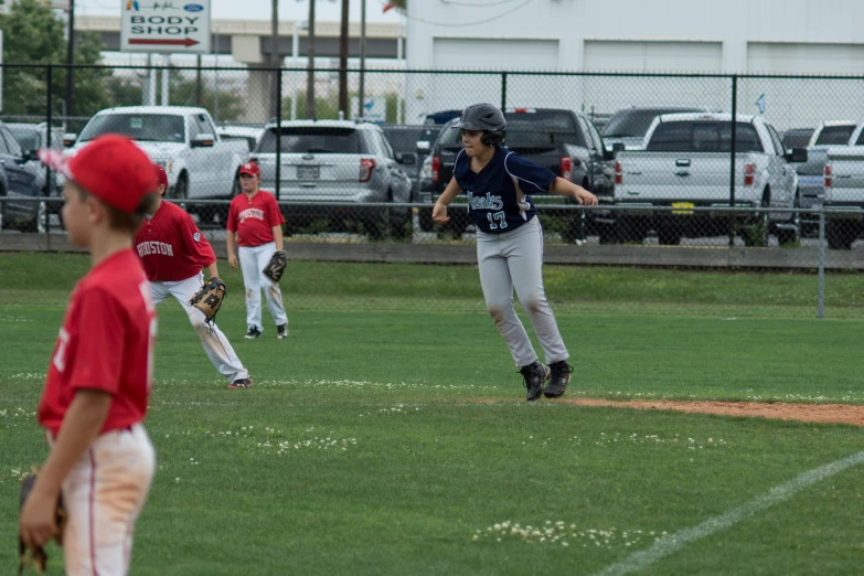 children wearing softball uniform play baseball on a green field