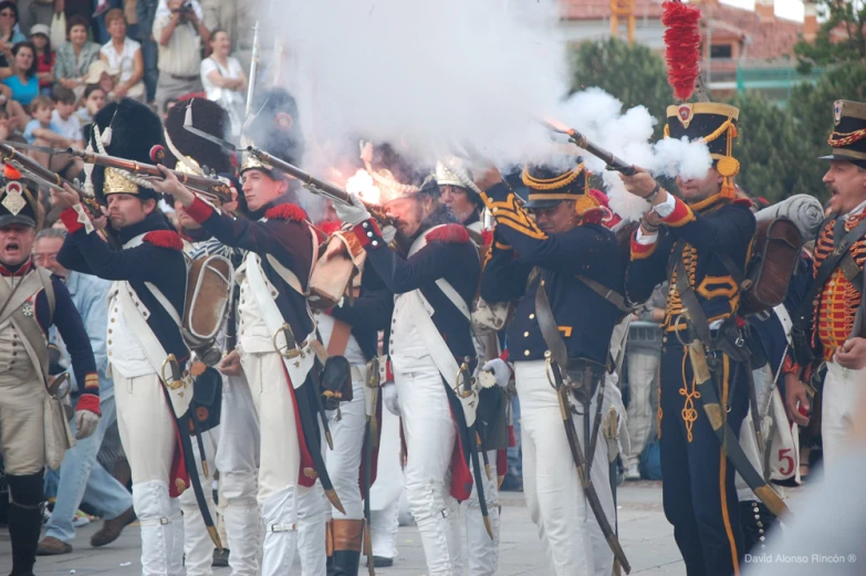 a parade of men in period uniforms with their pipes full of smoke
