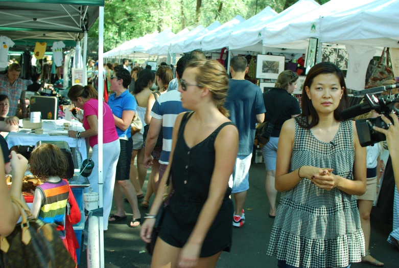 several people stand near many tables of objects for sale