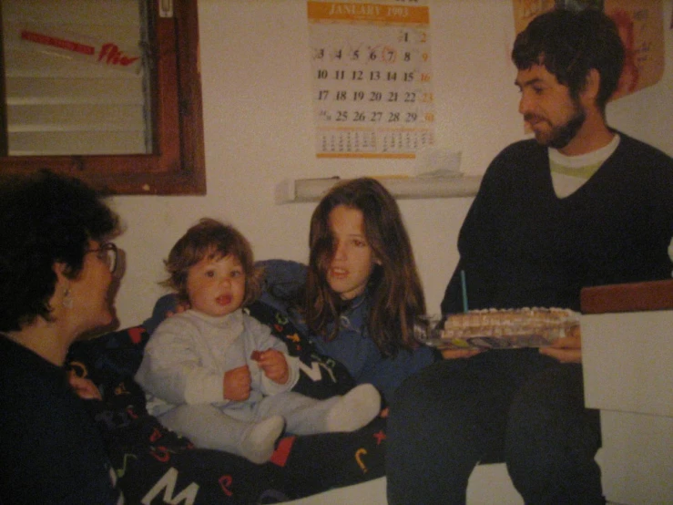 a family sitting on a couch in front of a calendar