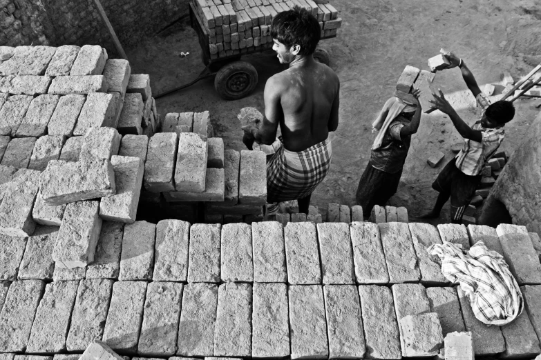 black and white po of men by a lot of bricks