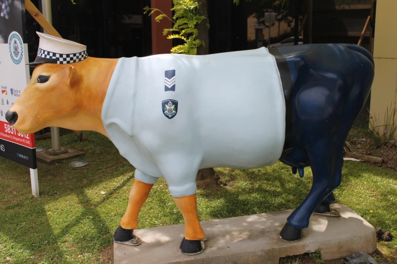 a cow statue with a police shirt on is outside