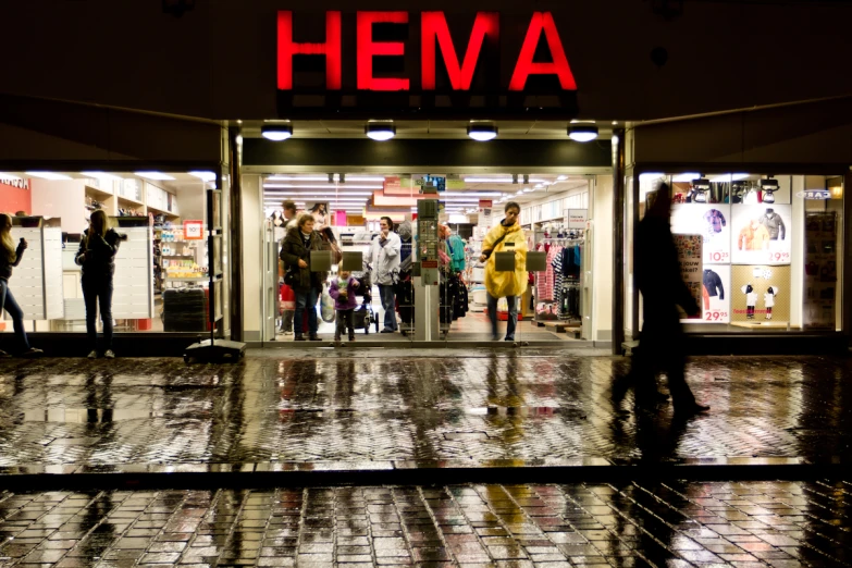 people waiting outside the entrance of a retail store at night