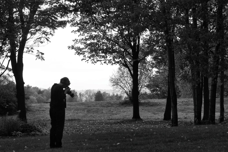 the man is standing in a forest looking at soing