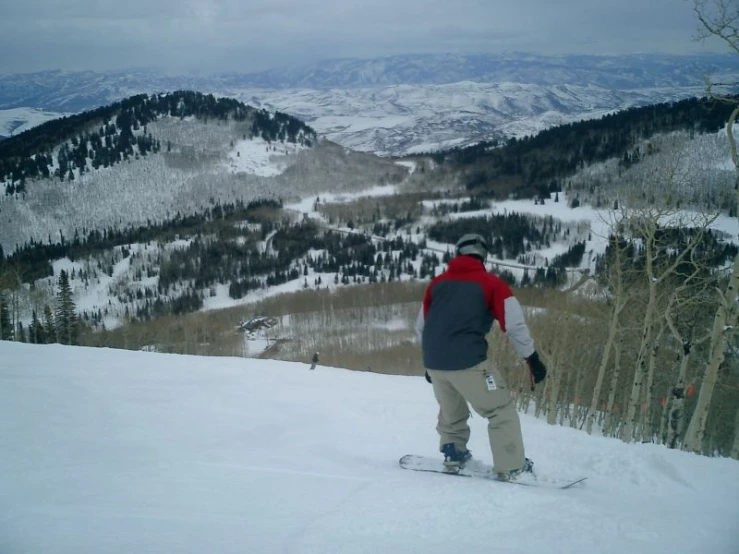 a person wearing a red and gray jacket on snow board