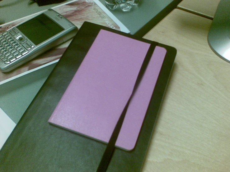 pink and black folders sitting on top of a wooden table