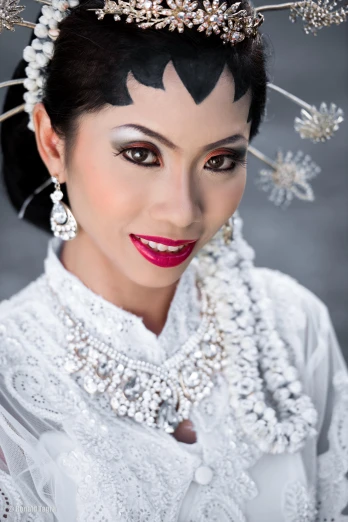 an asian woman in a white dress with silver jewelry and jewelry on her head