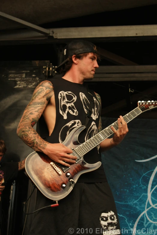a tattooed man playing guitar at a concert