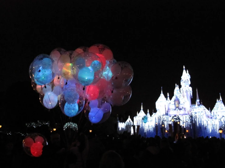 a castle with lights on at night is decorated in blue and pink