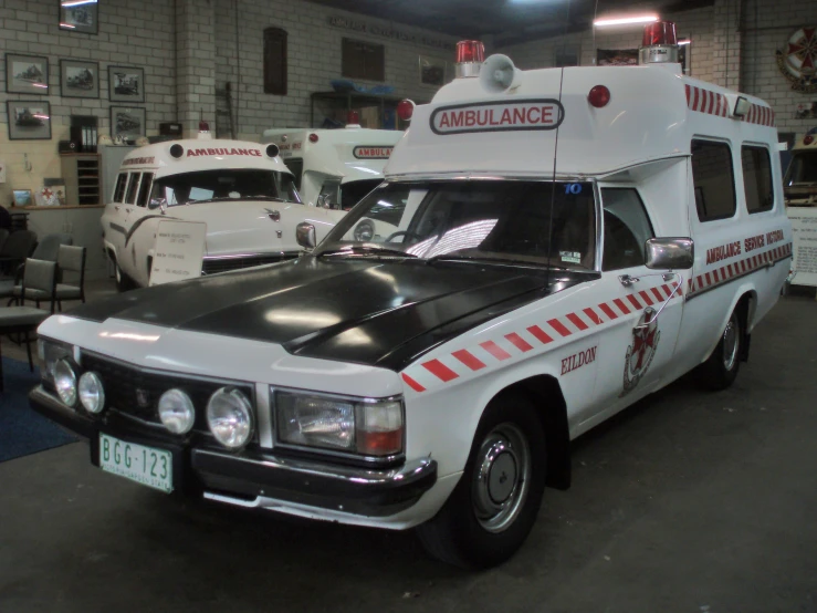 ambulances are lined up in a warehouse with other cars