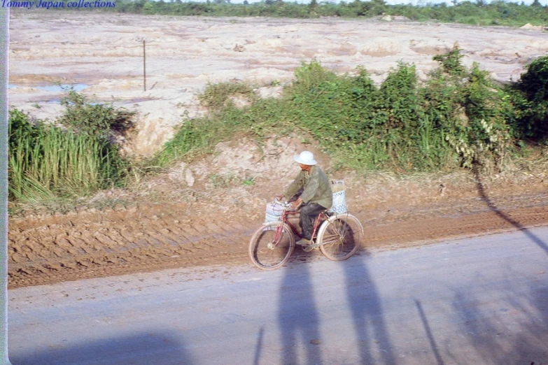 man riding his motorcycle down the road while standing in the dirt