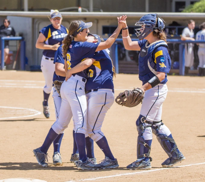 a group of girls in baseball uniforms congratulate each other