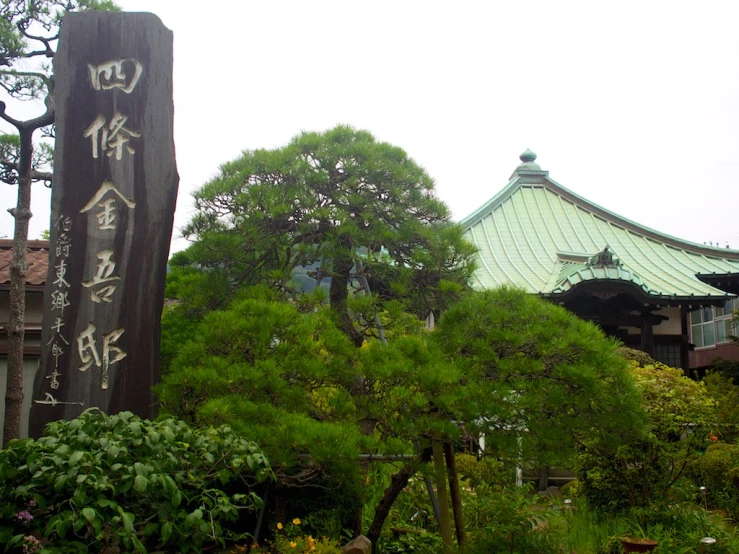 a wooden sign in front of a tree and other landscaping