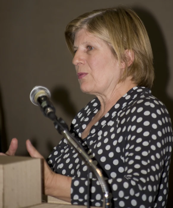 a woman talking into a microphone with white dots on it