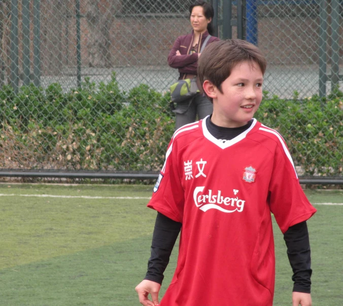 a boy in a red jersey smiles at the camera