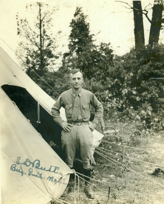 an old po of a man standing outside of a tent