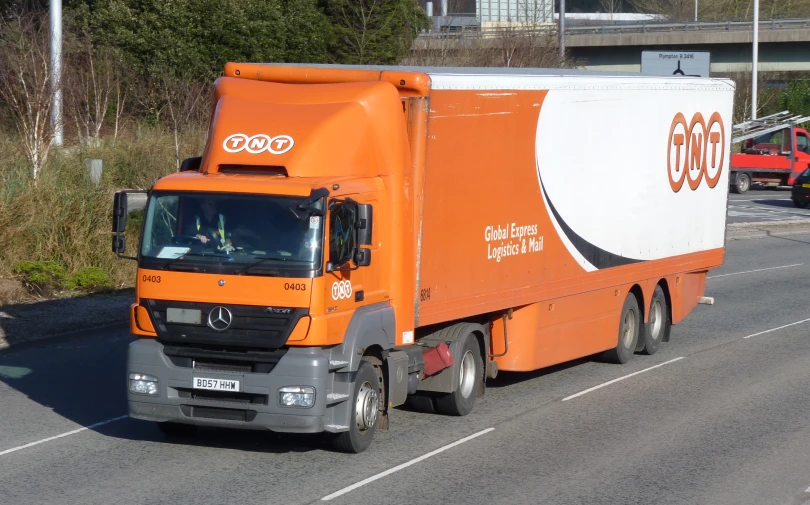 an orange truck traveling down the road with the olympic rings painted on it