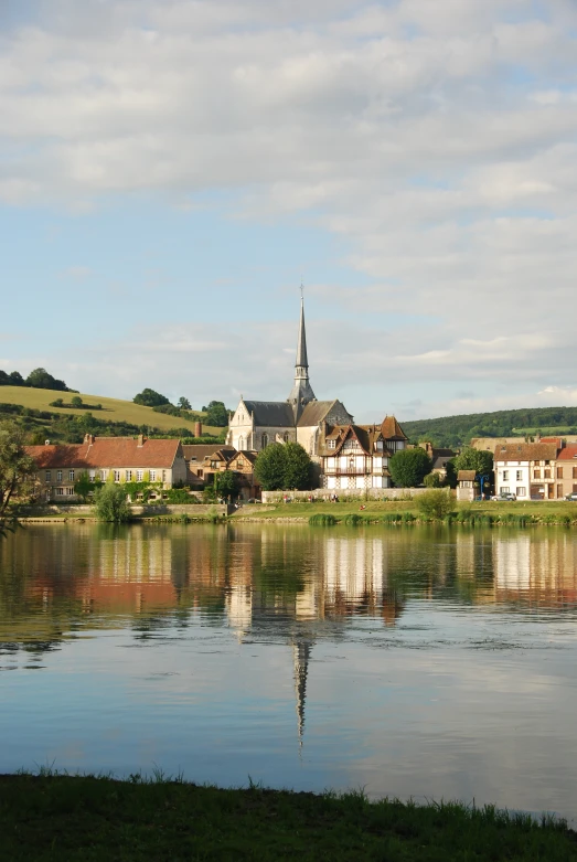 a house by the water on a hill in the background