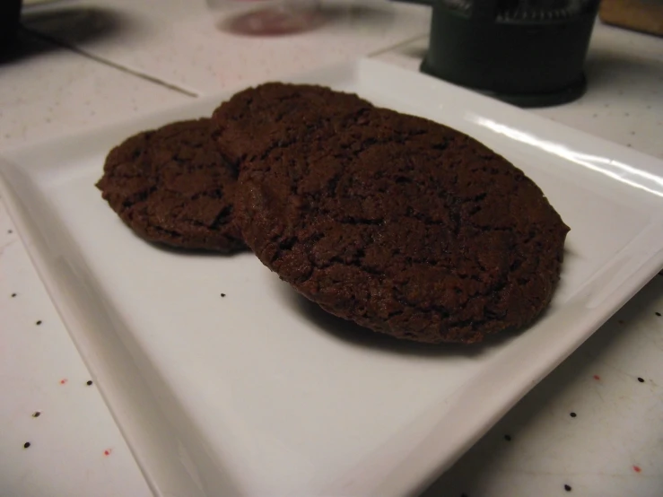 two pieces of chocolate cookies on a square white plate