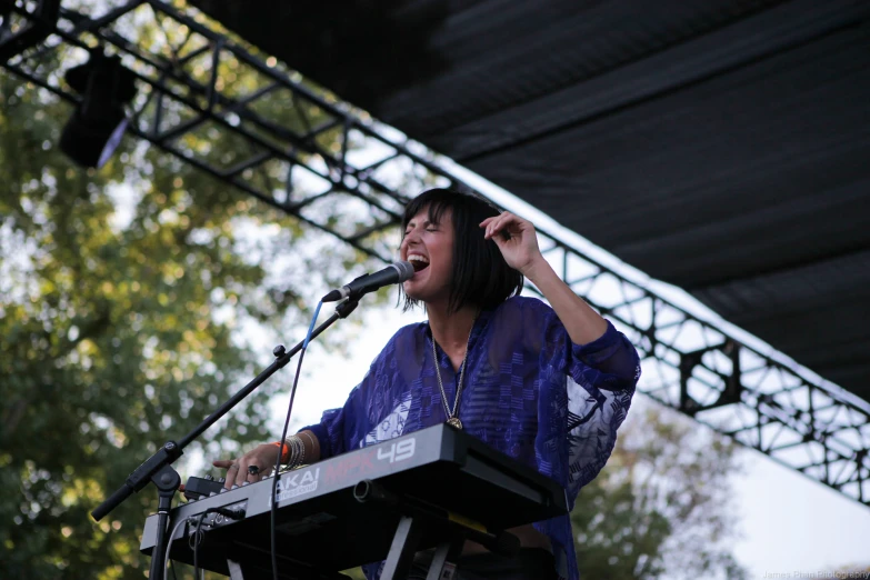 a person standing at a keyboard in front of a microphone