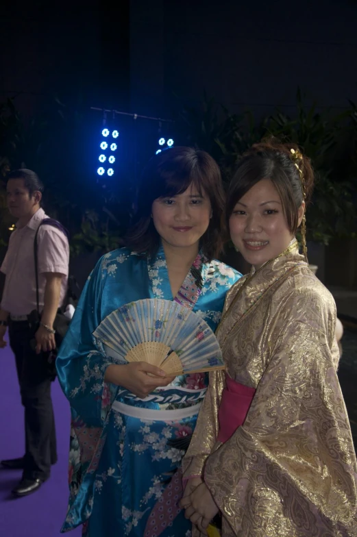 two women in oriental dress standing together smiling at the camera