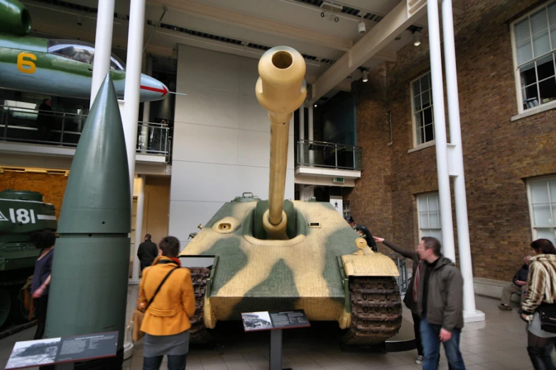 people standing around a tank with a dummy thing on it