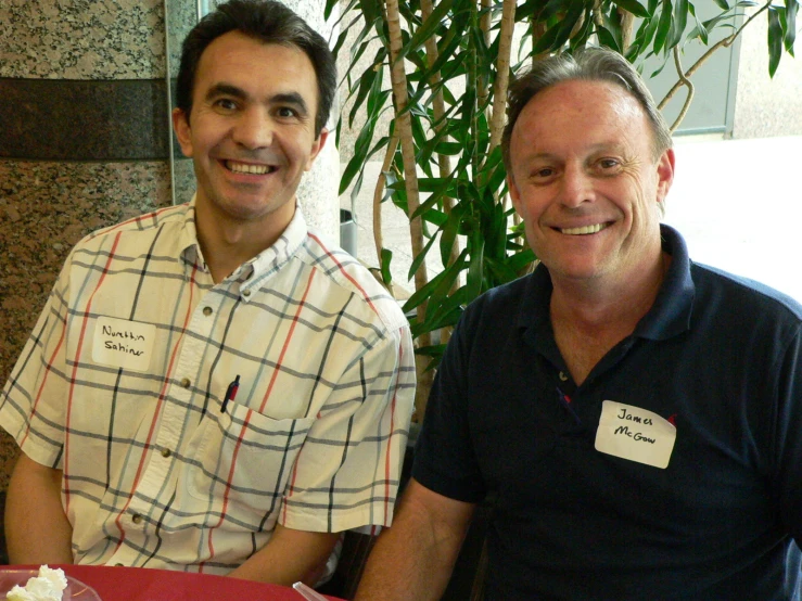 two men sitting at a table with a plate of food