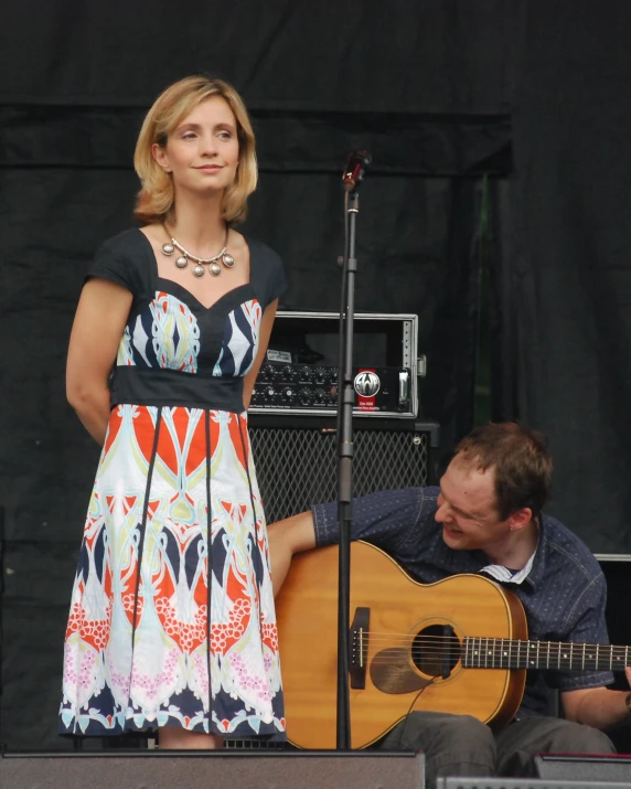 woman in a short dress playing a guitar next to a man